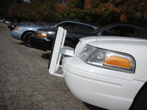 2004 Ford Crown Victoria - Several Ford Crown Victoria police interceptors are parked in a row, one with a push bumper visible.