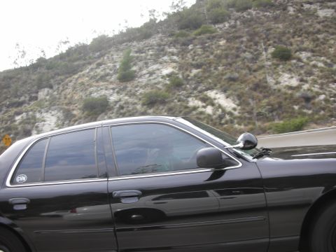 2004 Ford Crown Victoria - A black 2004 Ford Crown Victoria sedan is seen from the side while driving on a highway.