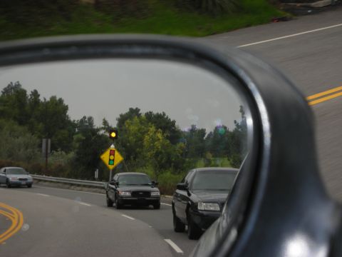 2004 Ford Crown Victoria - View of traffic and a traffic light in the side mirror of a vehicle on a road.