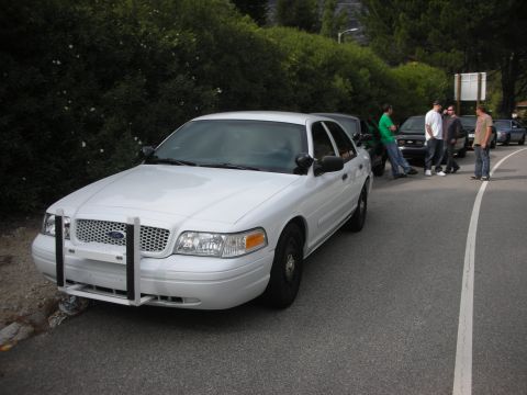 2004 Ford Crown Victoria - White 2004 Ford Crown Victoria with push bar parked on roadside, group of men standing nearby.