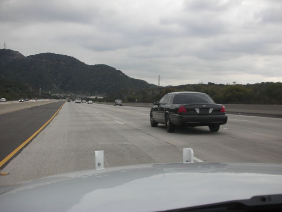Black 2004 Ford Crown Victoria sedan driving on a highway, rear view