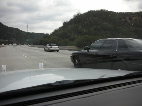 2004 Ford Crown Victoria - Driving on the highway with a black 2004 Ford Crown Victoria in the adjacent lane.
