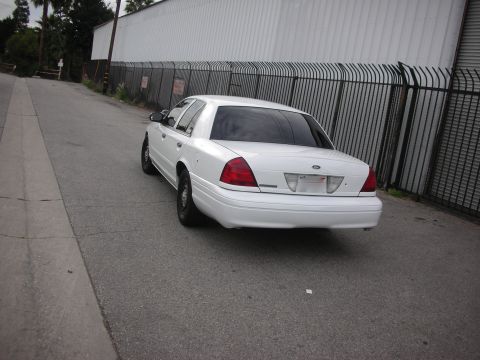 2004 Ford Crown Victoria - Rear view of a white 2004 Ford Crown Victoria parked on an asphalt road.