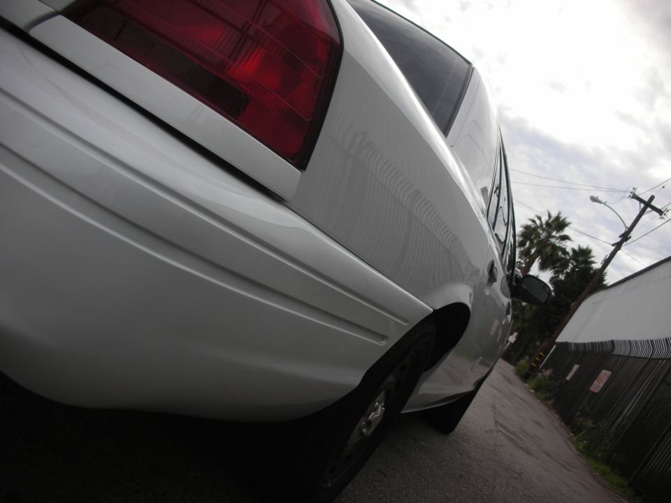 Rear quarter panel and taillight of a white sedan parked in an alley
