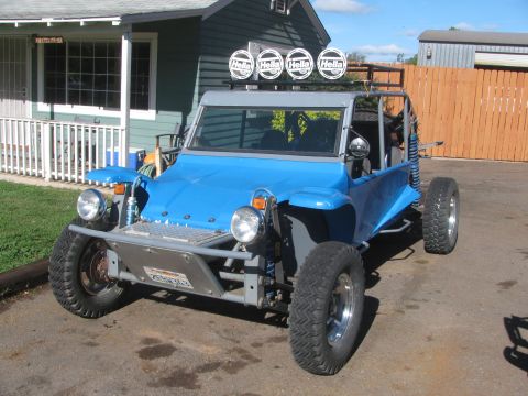 1990 Ford Bronco - blue open dune buggy with a row of four roof-mounted Hella lights and twin round headlights parked outside a house.