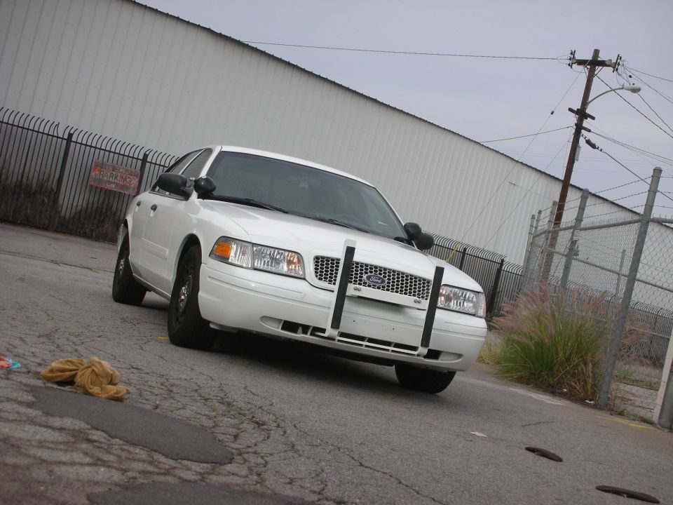 White 2004 Ford Crown Victoria police car parked on cracked asphalt, front view