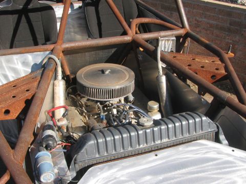 1990 Ford Bronco - V8 engine topped with a round chrome air cleaner sits mounted within a rusty tube-frame chassis.