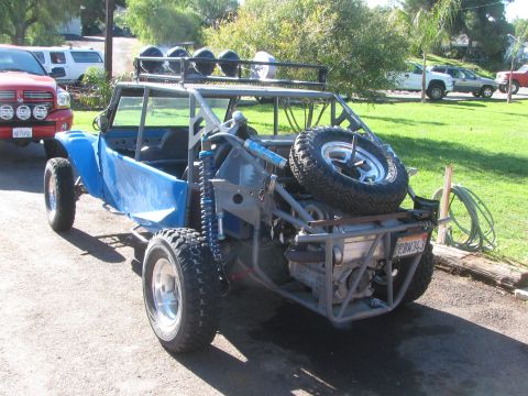 1990 Ford Bronco - Rear three-quarter view of a blue off-road buggy with roof lights and a spare tire mounted at the back, parked on a driveway.