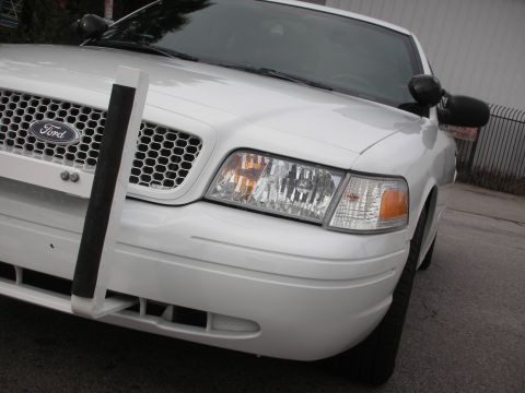 2004 Ford Crown Victoria - A white Ford Crown Victoria police car is shown from the front with a push bumper attached.