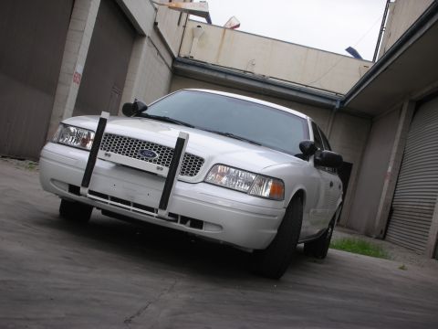 2004 Ford Crown Victoria - A white 2004 Ford Crown Victoria Police Interceptor is parked in a garage with a push bar on the front.