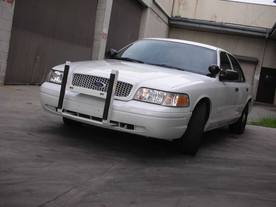 White Ford Crown Victoria with a push bumper parked outside a garage