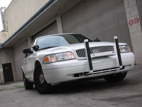 2004 Ford Crown Victoria - Front view of a white Ford Crown Victoria, equipped with a push bumper, parked outdoors.