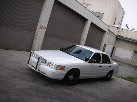 2004 Ford Crown Victoria - This 2004 Ford Crown Victoria is equipped with a push bumper and parked in front of a commercial building.