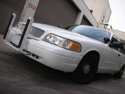 2004 Ford Crown Victoria - A white 2004 Ford Crown Victoria police car is parked in front of a garage door.