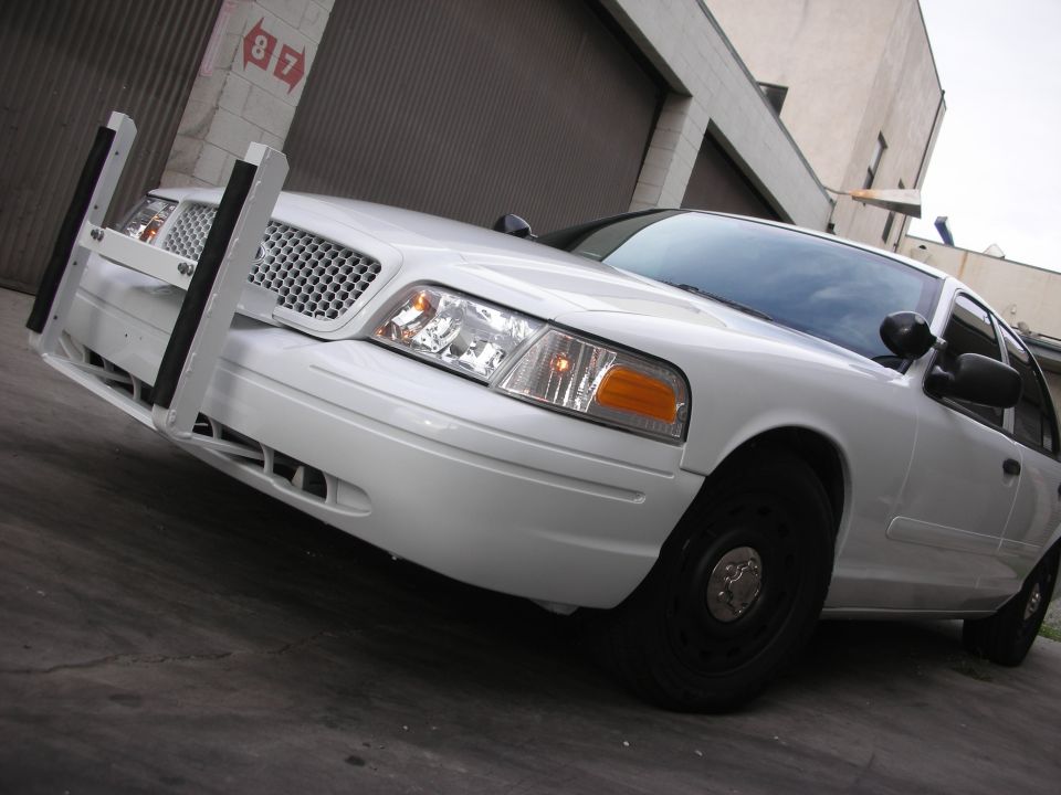 White 2004 Ford Crown Victoria police car with push bar, front quarter view, black steel wheels