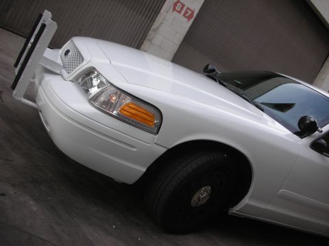 2004 Ford Crown Victoria - Front corner view of a white 2004 Ford Crown Victoria police car equipped with a push bumper.