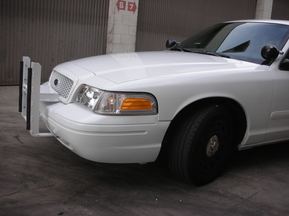 Front corner of a white Ford Crown Victoria with a push bumper and police spotlights