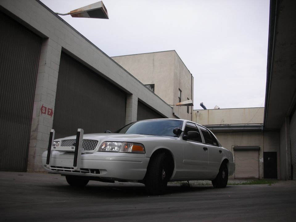 White 2004 Ford Crown Victoria police car with push bumper, front 3/4 view