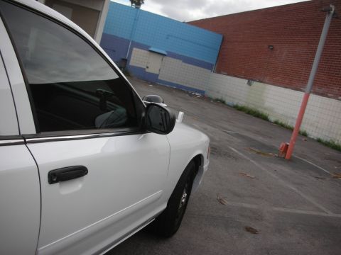 2004 Ford Crown Victoria - Side view of a white 2004 Ford Crown Victoria parked in an urban area.