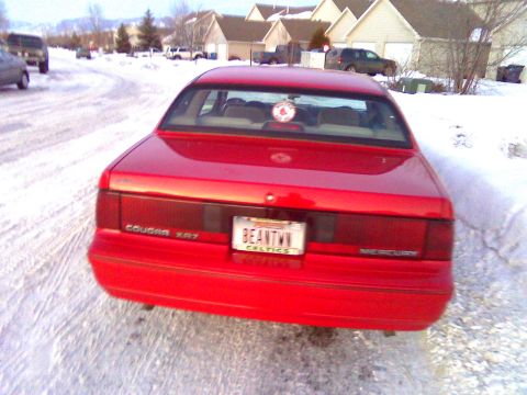 2006 Ford E350 - Rear view of a red Mercury Cougar XR7 parked on a snowy street, with houses in the background.