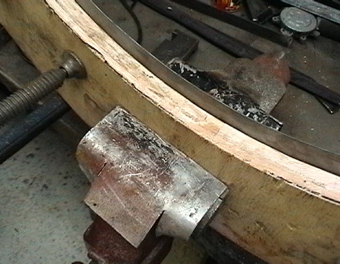 Metal pipe clamped to a wooden jig with a metal band