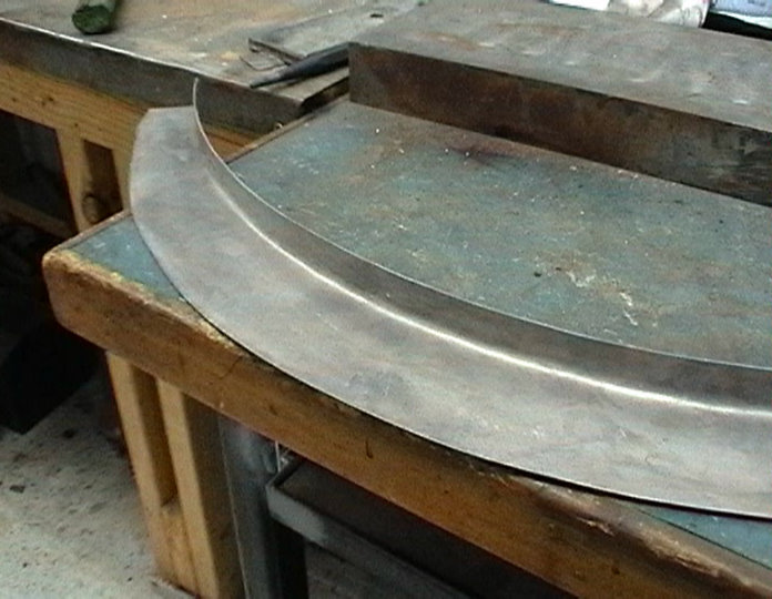 Curved metal part on workbench