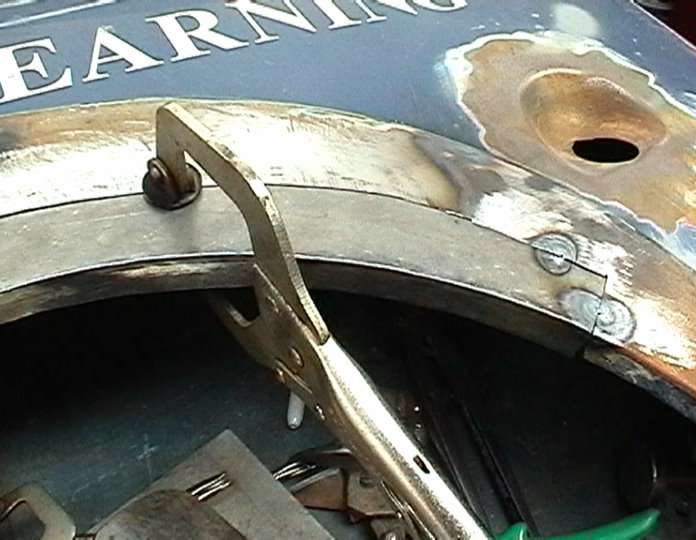 Car body panel with vice grips holding a metal piece in place during repair