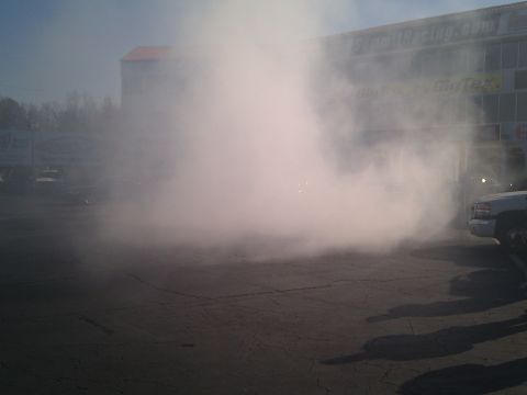 2001 Ford Crown Victoria - A truck is performing a burnout, creating a large cloud of smoke. A building with signage is in the background.