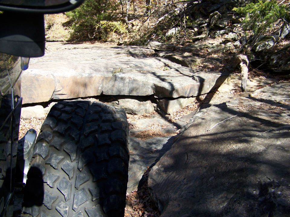 Off-road tire on a vehicle navigating large rocks on a trail
