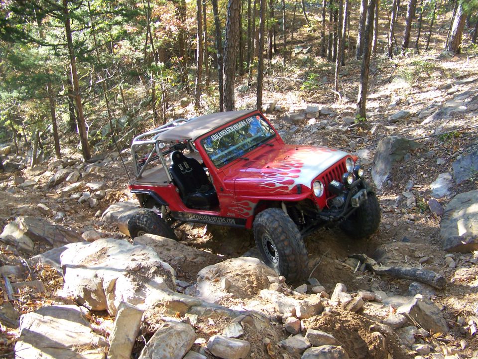 Red Jeep Wrangler with flame decals navigating a rocky trail