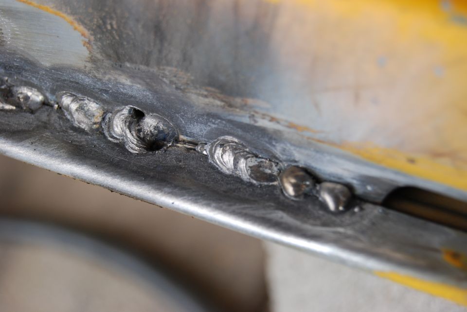 Close-up of welds on yellow and gray metal panel