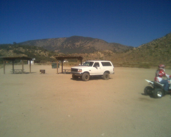 White lifted Bronco SUV and ATV rider in a desert staging area