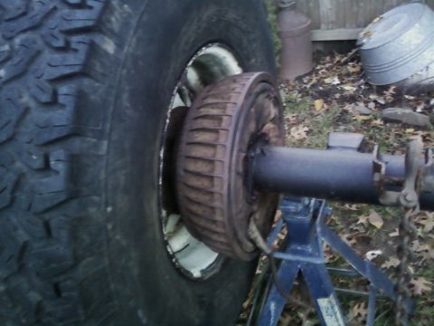 1990 Ford Bronco - Close-up of a vehicle's rear axle and drum brake assembly, supported by jack stands.