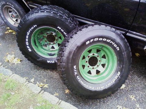 1990 Ford Bronco - BFGoodrich All-Terrain T/A tires on green rims, with a black vehicle visible behind them.