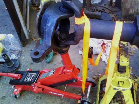 1990 Ford Bronco - Vehicle suspension components are supported by jacks and straps, suggesting repair or maintenance work.