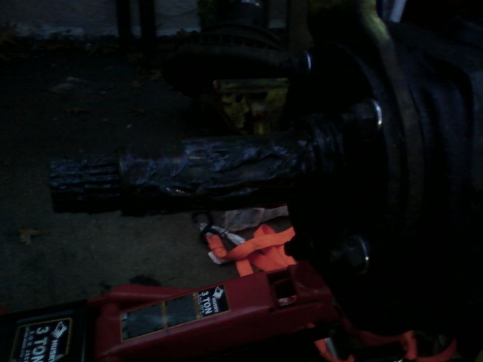 Axle housing tube on pavement supported by red 3-ton floor jack and orange strap