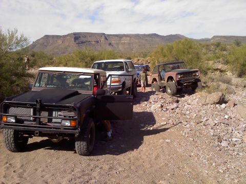 1996 Ford Bronco - Several off-road vehicles, including a Bronco and an F-150, are parked in a desert landscape.
