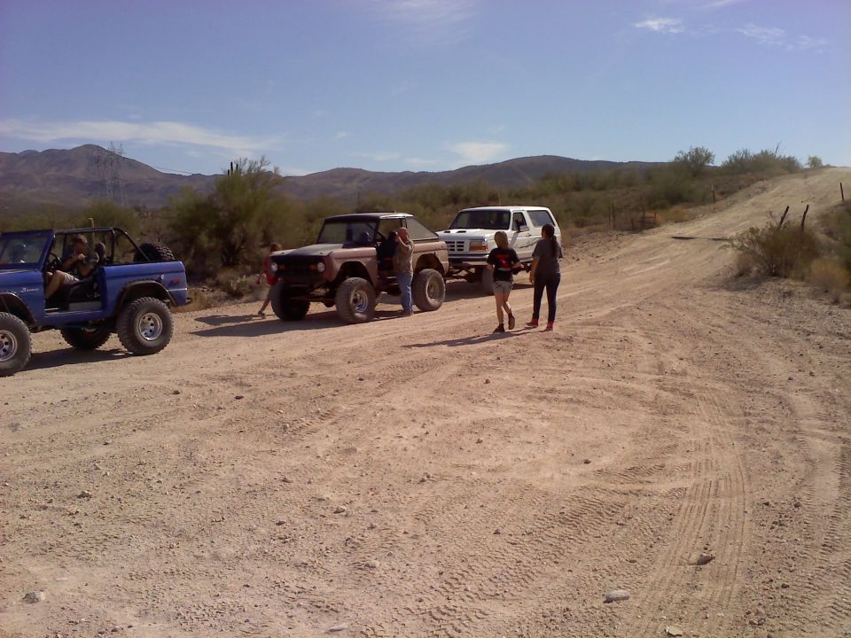 Brown Ford Bronco with a black top, parked on a dirt road