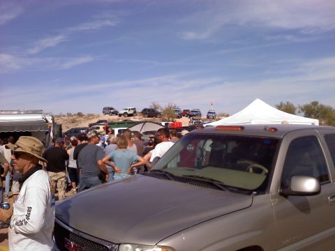 1996 Ford Bronco - A group of people gather around vehicles in a desert landscape under a clear blue sky.