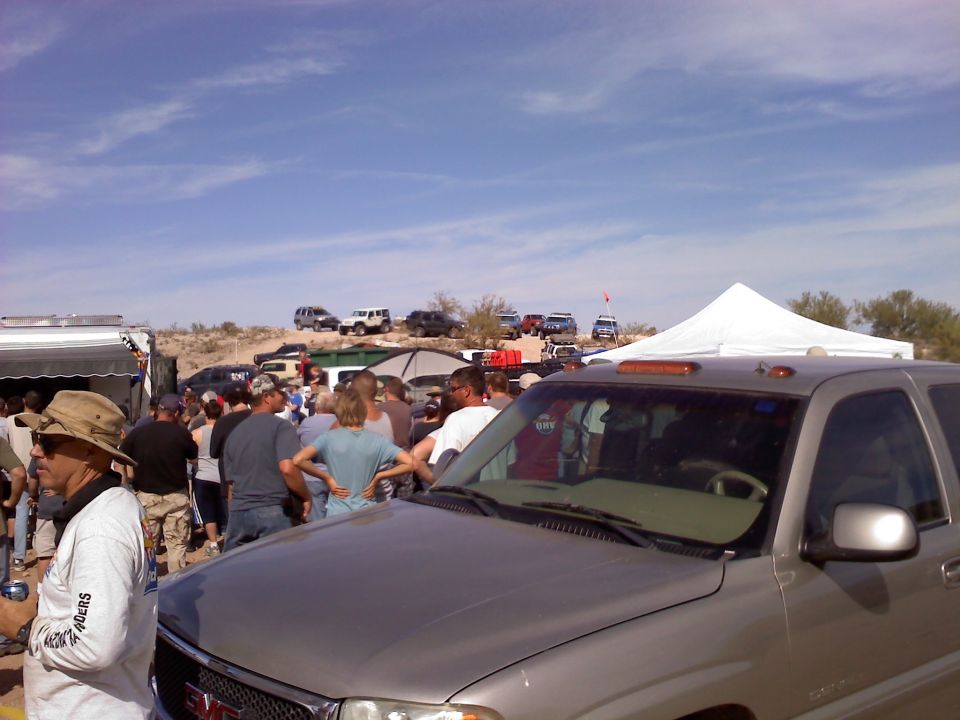 Silver GMC pickup truck front 3/4 view with people and other vehicles in background