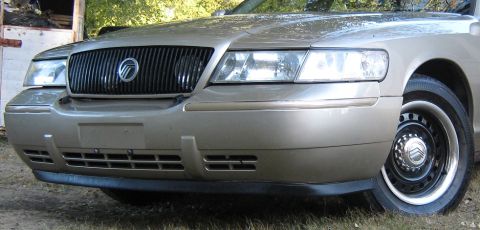 2000 Mercury Grand Marquis - Front view of a gold 2000 Mercury Grand Marquis, highlighting its distinctive vertical grille and headlights.
