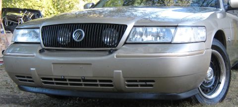 2000 Mercury Grand Marquis - Gold 2000 Mercury Grand Marquis front end with a prominent black grille and headlights.
