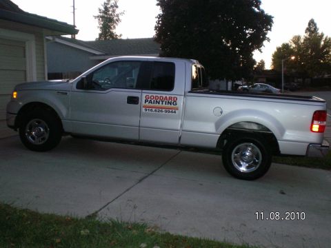 1996 Ford Bronco - A silver pickup truck is parked in a driveway next to a garage.