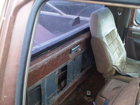 1992 Ford Bronco - Interior view of a brown vehicle, a tan seat and worn door panel. The registry claims it's a 1992 Ford Bronco, but visual evidence is incon…