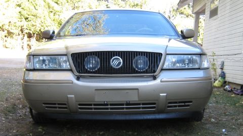 2000 Mercury Grand Marquis - Front view of a gold 2000 Mercury Grand Marquis, its distinctive vertical grille and dual round headlights.