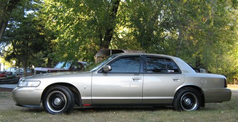 2000 Mercury Grand Marquis - Side view of a gold 2000 Mercury Grand Marquis sedan parked outdoors.