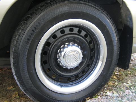 2000 Mercury Grand Marquis - Close-up of a car wheel a Mercury logo on the hubcap and a Firestone tire.