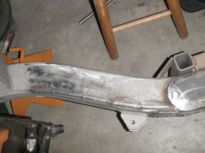 Bare steel frame rail with long MIG weld bead along a lengthened frame seam