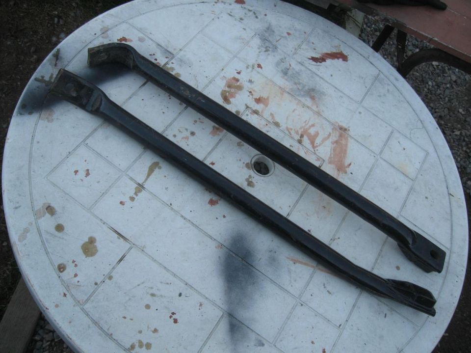 Two black metal bars with angled ends on a white plastic table with stains