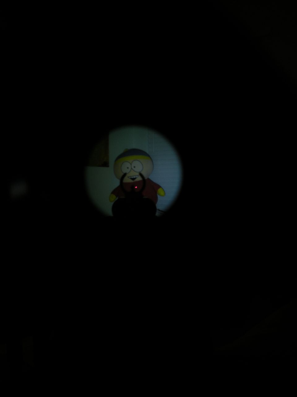 Toy character viewed through a scope with a red dot sight